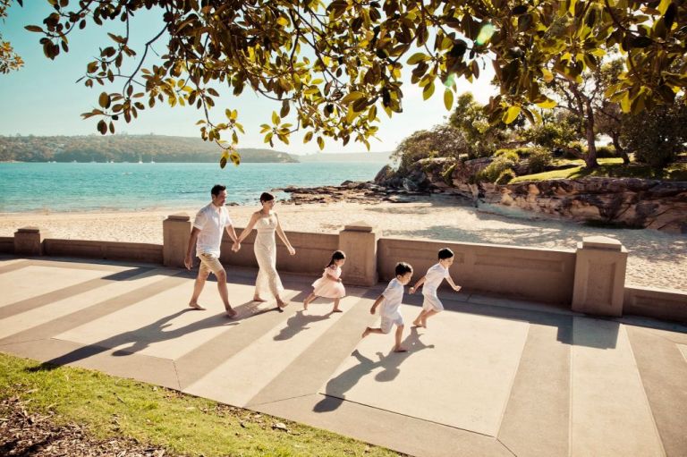 capture family moments in Sydney - a photo of a family walking down a sidewalk next to the ocean.
