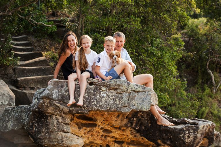 outdoor pet photography sessions - picture of a family sitting on a rock with a dog